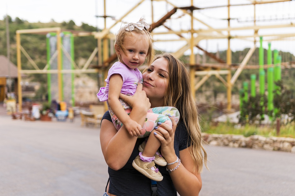 Mother and child at Cave of The Winds adventure park in front of ropes course in the daylight.